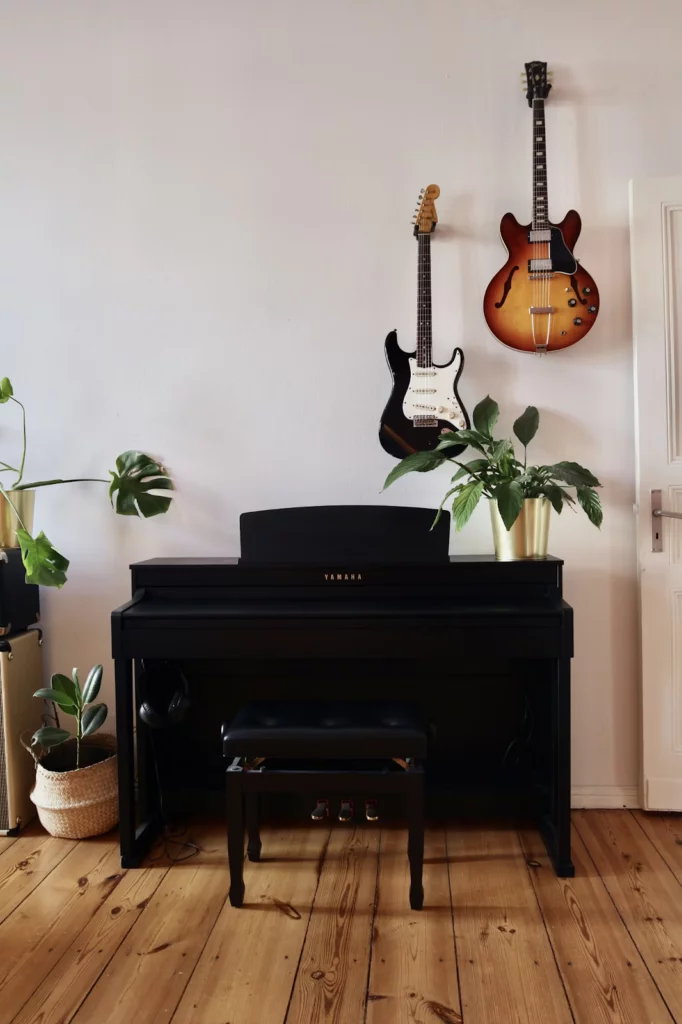  piano da yamaha preto em sala com paredes brancas e chão de taco marrom.