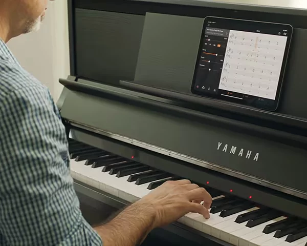 Homem tocando piano digital Clavinova.